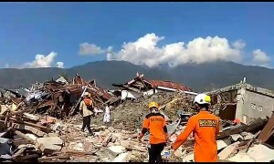 Rescuers walk through piles of rubble in aftermath of deadly Indonesia earthquake