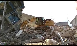 Excavator digs through debris from fallen hotel on earthquake-stricken Indonesia island