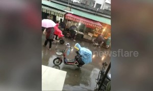 Small boy keeps his mum's bike seat dry in the rain with his own body