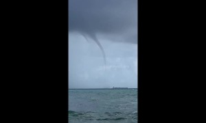 Water spout looms low over cargo ship