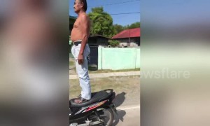 Drivers amazed by elderly man standing on moving motorcycle