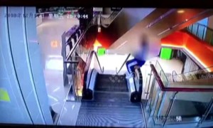Naughty student climbs onto escalator handrail and falls one storey