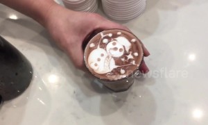 Skilled barista draws intricate snowman on hot chocolate drink