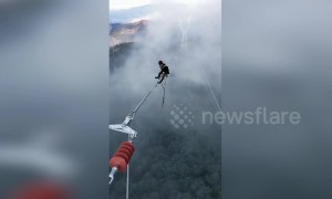 Chinese electricians work on power lines hundreds of feet above the ground