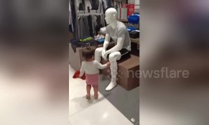 Adorable moment polite toddler greets mannequins inside shopping mall