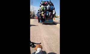 Dozens of students risk their lives clinging to outside of moving bus in India