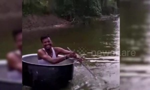 Man rows over water in cooking pot boat with spatula paddle
