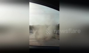 Terrified driver watches as dust devil approaches his car