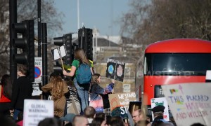 School children climb lamp posts during central London climate protest