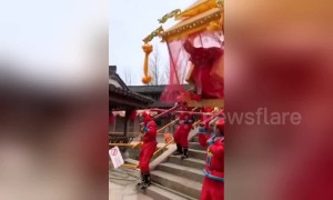 Woman tumbles out of sedan chair going downhill over bridge