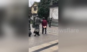 Chinese granny uses pointy finger on statue to scratch her back