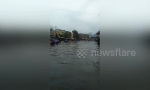 Hundreds of women wade through waist high water after road floods in Indonesia