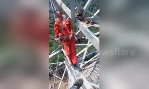 Chinese electrical workers nap on 50-metre-high transmission tower