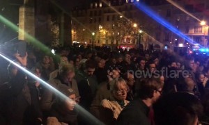 Parisians gather and sing hymns on the Tournelle Bridge opposite Notre Dame