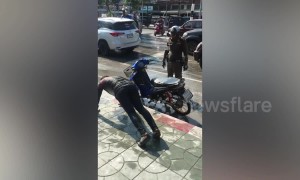 Policeman makes motor scooter rider do push-ups as punishment