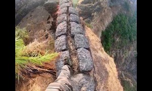 Trekker takes a high risk walk along edge of a mountain fort in central India