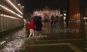 Tourists forced to wade as unusually high tide floods Venice