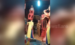 Woman in Vietnam uses her mouth to lift a child and chair over her head
