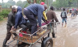 Pedestrians pay 10p to be taken across fast moving flood waters in Kenya