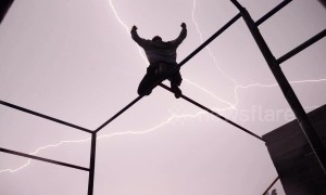 Free runner strikes a pose perfectly as bolts of lightning ignite the sky