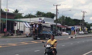 Reckless schoolboys climb onto roof of moving bus on busy road in Thailand