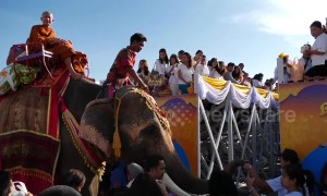 Thai monks ride elephants while receiving donations to mark the start of Buddhist Lent