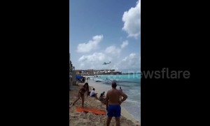 Beachgoers watch as planes fly low over Caribbean beach