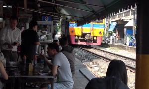 Locals eat at tables just inches from passing trains at Thai restaurant