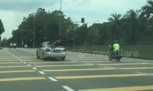 Reckless driver in Malaysia is caught jumping red light with two children clinging to roof