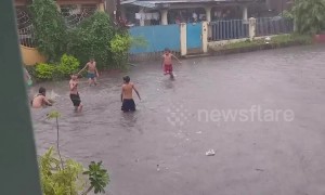 Filipino children make the most of the bad weather by playing in flooded street