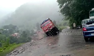 Pedestrians watch on as truck topples off cliff during landslide in northern India