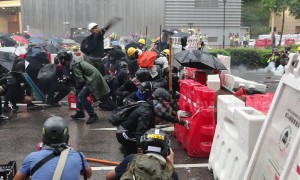 Hong Kong protesters take cover behind barricades as police fire tear gas