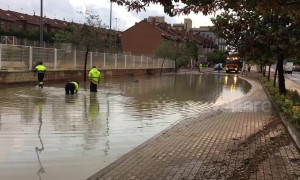Road maintenance workers attempt to drain road after storm batters Madrid