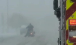 Firetruck Escorts Motorcycle Through the Snow
