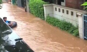 Kid floats down tube in flooded streets of Jakarta