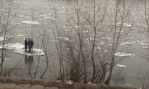 People Floating on Ice in a River