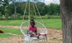 Little boy enjoys hammock swing with his puppy