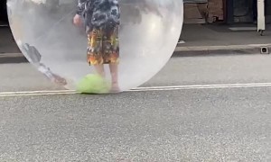 Performer Sings in Bubble While Rolling Down the Road