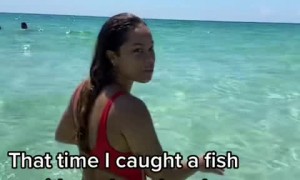 Woman in the ocean catches fish with her bare hands  