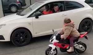Kid on Toy Motorbike Challenges Driver to a Race