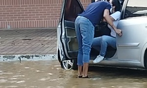Man Carries Woman to Car in Flooded Street