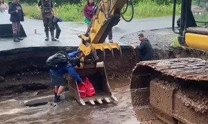 Man Uses Backhoe To Cross Washed Out Road and Bring Home Groceries