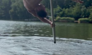 Man Dances On Flying Pole Over Peaceful Lake