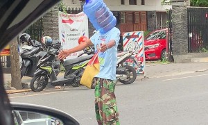 Man Directing Traffic Wears Water Jug in Indonesia