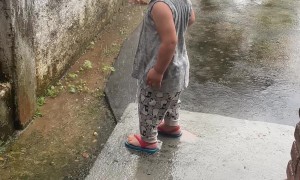 Boy Splashes In Rain Gutter Runoff