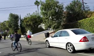 Car Races Through Large Pack Of Bicycles