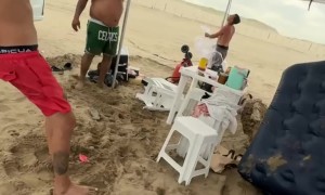 Beachgoers Fight Storm to Keep Their Canopy
