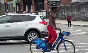 Man Rides Bike While Balancing a Fridge on His Head