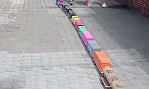 Little Boy Walks Giant Train Down Sidewalk