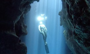 Cave View of a Free Diver Swimming Through Bubble Rings
